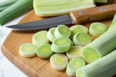 Kırpılmış pırasa, bıçak ve tahta beyaz masa, yakın plan.