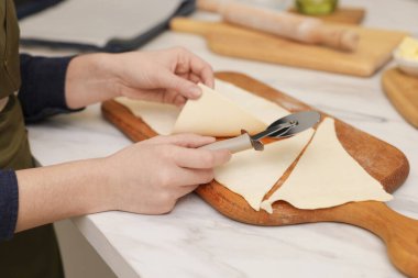 Hafif mermer masada hamuru kesen kadın, yakın plan. Kruvasan yapıyorum.