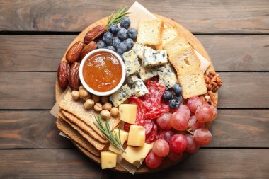 Tahta masa ve üst manzara üzerinde çeşitli lezzetli peynir ve diğer atıştırmalıklar.