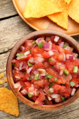 Tabakta nefis salsa ve ahşap masada nacho cipsi.