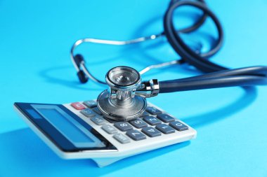 Açık mavi arkaplanda stetoskop ve hesap makinesi, yakın plan
