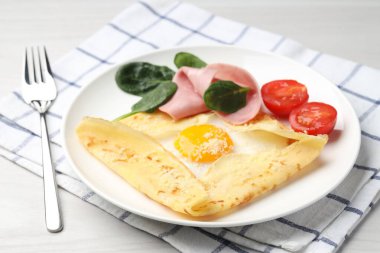 Beyaz masada servis edilen yumurta, jambon ve parmesan peynirli leziz krep.
