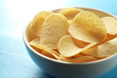 Açık mavi ahşap masada patates cipsi, yakın plan.