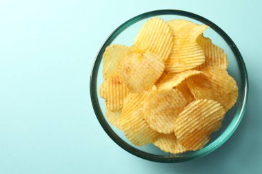 Açık mavi arka planda leziz patates cipsleri, üst manzara. Metin için boşluk