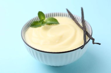 Lezzetli vanilyalı puding, nane ve kapsüller açık mavi arka planda, yakın plan