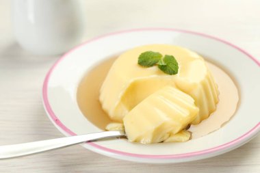 Karamel soslu lezzetli puding ve beyaz masada servis edilen nane şekeri.