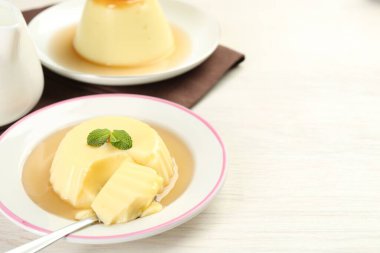Karamel soslu lezzetli puding ve beyaz masada servis edilen nane. Metin için boşluk