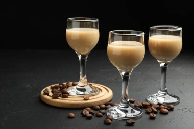 Coffee cream liqueur in glasses and beans on black table