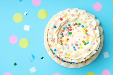 Renkli süslemeli nefis bento keki ve açık mavi masada konfeti, düz konfeti. Metin için boşluk