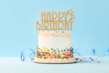 Delicious bento cake with colorful sprinkles, topper and serpentine streamer on white table
