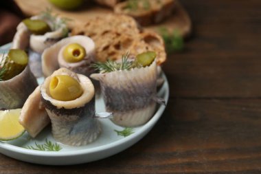 Zeytinli, turşulu ve ahşap masada dereotlu ringa dürümleri. Yakın plan. Metin için boşluk