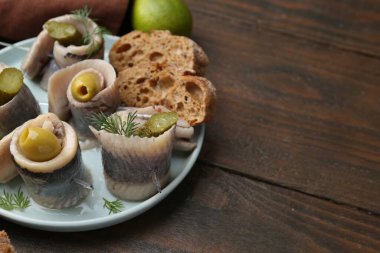 Lezzetli ringa dürümleri zeytin, turşu, dereotu ve ekmek parçaları ahşap masada, yakın plan.