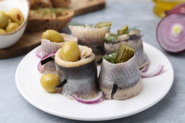 Gri masada zeytinli, turşulu, dereotlu ve soğanlı lezzetli ringa dürümleri.