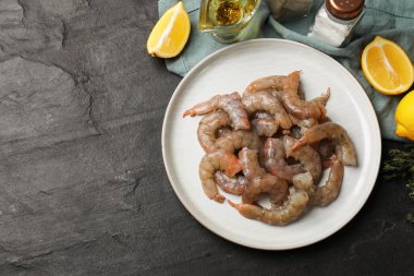 Gri masada taze çiğ karides, baharat ve limon dilimleri. Metin için boşluk