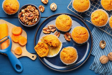Lezzetli havuçlu kekler, cevizler ve taze sebzeler mavi ahşap masada, düz uzanmış