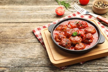 Fırın kabında domates soslu leziz köfteler ve ahşap masada baharatlar, yakın plan. Metin için boşluk