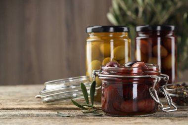 Cam kavanozlarda zeytin turşusu ve ahşap masada baharatlar, yakın plan. Metin için boşluk