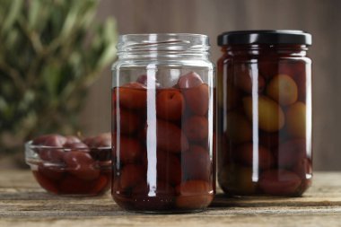 Cam kavanozlarda zeytin turşusu ve ahşap masada kase, yakın plan.