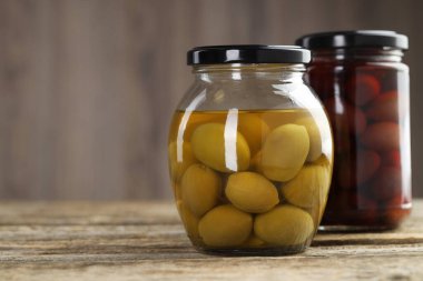 Ahşap masada cam kavanozlarda zeytin turşusu, yakın plan. Metin için boşluk