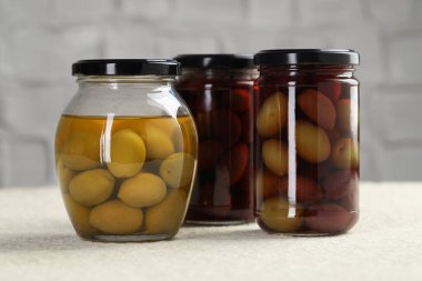 Kavanozlarda turşulu yeşil zeytin beyaz desenli masa, yakın çekim.