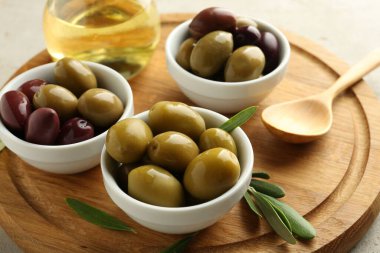 Lezzetli marine edilmiş zeytinler kaseler, kaşık, yağ ve yeşil yapraklar masada, yakın çekim