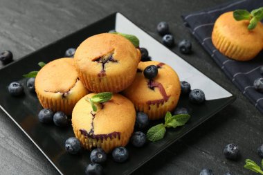 Yaban mersinli lezzetli kekler ve koyu dokulu masada nane şekeri, yakın plan.