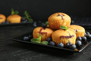 Yaban mersinli lezzetli kekler ve koyu dokulu masada nane şekeri, yakın plan.