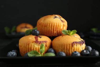 Yaban mersinli lezzetli kekler ve siyah arkaplanlı nane şekeri, yakın plan.