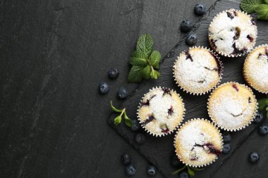 Yaban mersinli lezzetli çörekler, pudra şekeri ve siyah desenli masada nane şekeri, düz yatak. Metin için boşluk