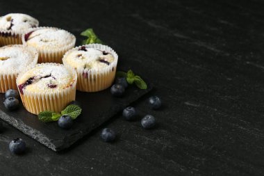 Yaban mersinli lezzetli çörekler, pudra şekeri ve siyah desenli masada nane şekeri, yakın plan. Metin için boşluk