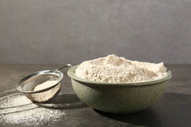 Kahverengi pirinç unu ve elek gri masada. Metin için boşluk