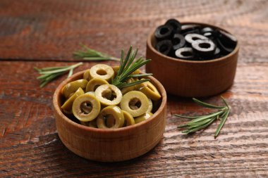 Farklı lezzetlerde marine edilmiş zeytin halkaları ve ahşap masada biberiye, yakın plan.