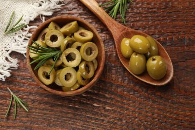 Lezzetli marine edilmiş zeytin halkaları kasede, kaşık dolusu ve ahşap masada biberiye, düz uzanmış.