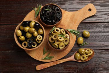 Farklı lezzetlerde marine edilmiş zeytin halkaları, bütün halkalar ve ahşap masa üzerinde biberiye, düz uzanış
