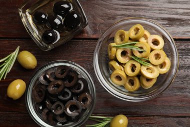 Farklı lezzetlerde marine edilmiş zeytin halkaları, bütün halkalar ve ahşap masa üzerinde biberiye, düz uzanış