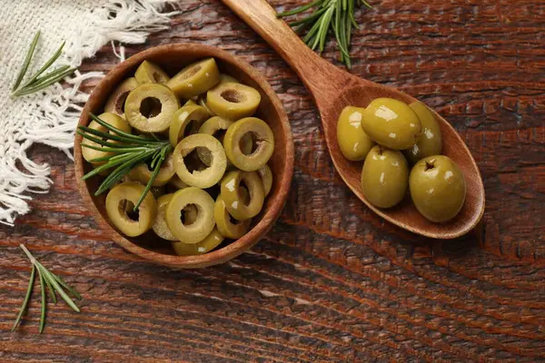 Lezzetli marine edilmiş zeytin halkaları kasede, kaşık dolusu ve ahşap masada biberiye, düz uzanmış.
