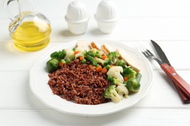 Sebzeli lezzetli kahverengi pirinç ve beyaz ahşap masada tavuk, yakın plan.