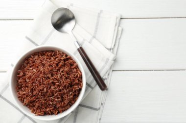 Lezzetli kahverengi pirinç kasede ve kaşıkla beyaz ahşap masa, üst manzara. Metin için boşluk