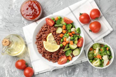 Gri desenli masada servis edilen sebzeli ve limon dilimli lezzetli kahverengi pirinç.