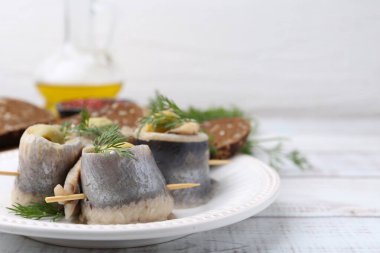 Zeytinli lezzetli ringa dürümleri, beyaz ahşap masada dereotu ve ekmek, yakın plan. Metin için boşluk