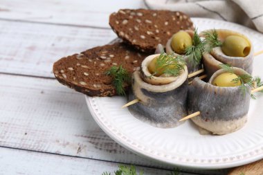 Zeytinli lezzetli ringa dürümleri, beyaz ahşap masada dereotu ve ekmek, yakın plan. Metin için boşluk