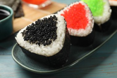 Lezzetli tobiko onigiri (Japon pirinç topları) açık mavi ahşap masa üzerinde, yakın plan