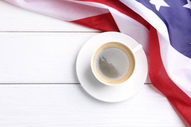 Bir fincan kahve ve beyaz ahşap masada Amerikan bayrağı, üst manzara. Metin için boşluk