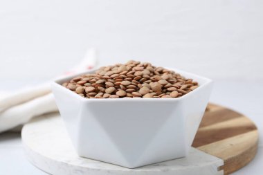 Beyaz masada çiğ kahverengi mercimek, yakın plan.