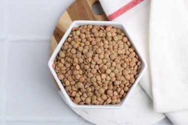 Beyaz döşeme üzerinde çiğ kahverengi mercimek, üst manzara.