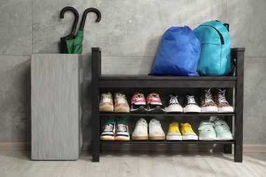 Ayakkabı bankı, farklı ayakkabılar, sırt çantası, spor çantası ve şemsiyeler.