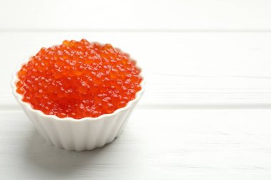 Beyaz ahşap masada, kasede kırmızı havyar, yakın plan. Metin için boşluk