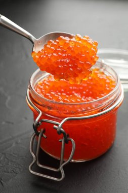 Gri masadaki cam kavanozdan kaşıkla lezzetli kırmızı havyarı alıp yakın plan çekiyoruz.