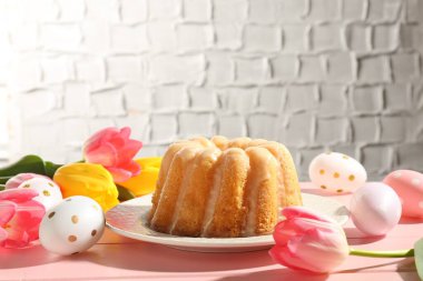 Lezzetli kek, Paskalya yumurtası ve pembe ahşap masada laleler.