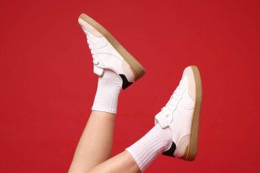 Kırmızı arka planda şık ayakkabılar giyen kadın, yakın plan.